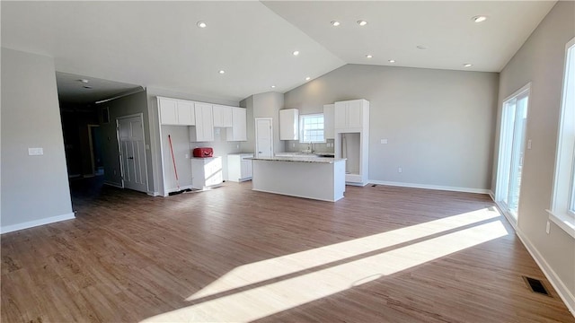 kitchen with white cabinets, light stone counters, a kitchen island, and light hardwood / wood-style floors