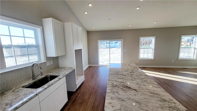 kitchen featuring white cabinetry, tasteful backsplash, light stone counters, and sink