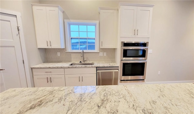 kitchen with white cabinets, sink, decorative backsplash, light stone counters, and stainless steel appliances