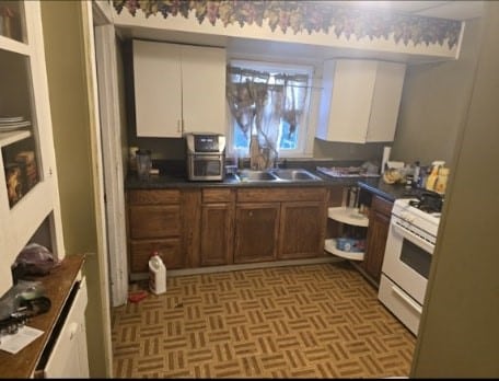 kitchen with white range oven, white cabinetry, and sink