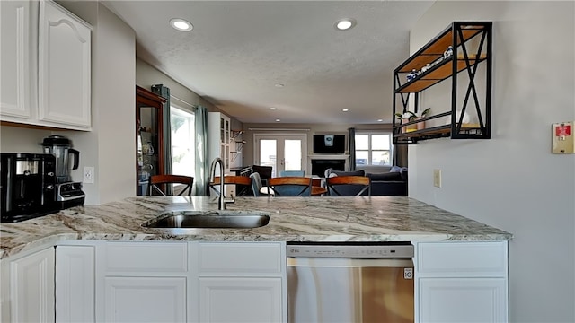 kitchen with dishwasher, white cabinetry, sink, and light stone countertops