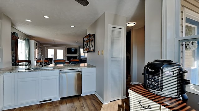 kitchen featuring stainless steel dishwasher, hardwood / wood-style flooring, white cabinets, and sink