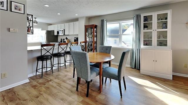 dining room with a textured ceiling and light hardwood / wood-style floors