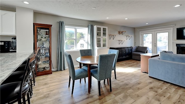 dining space with french doors, light hardwood / wood-style flooring, and a healthy amount of sunlight