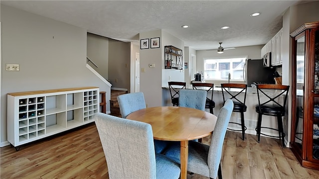 dining space featuring light hardwood / wood-style floors, ceiling fan, and a textured ceiling