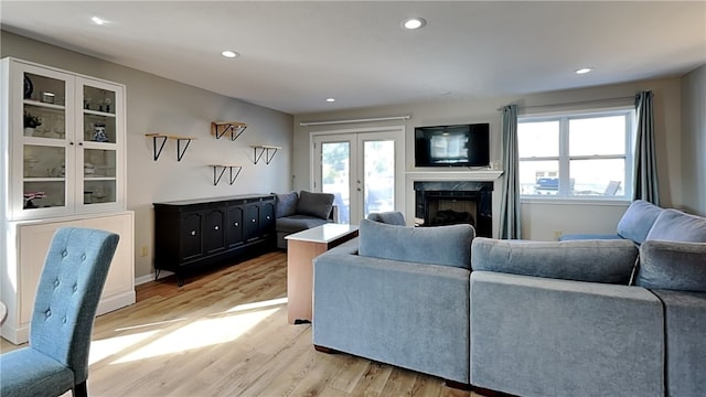 living room with a fireplace, light hardwood / wood-style floors, and french doors