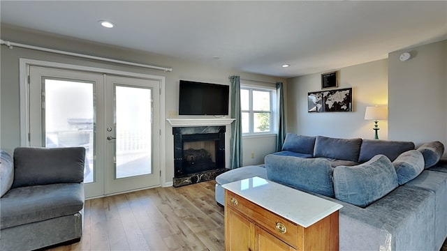 living room featuring light hardwood / wood-style floors, a high end fireplace, and french doors