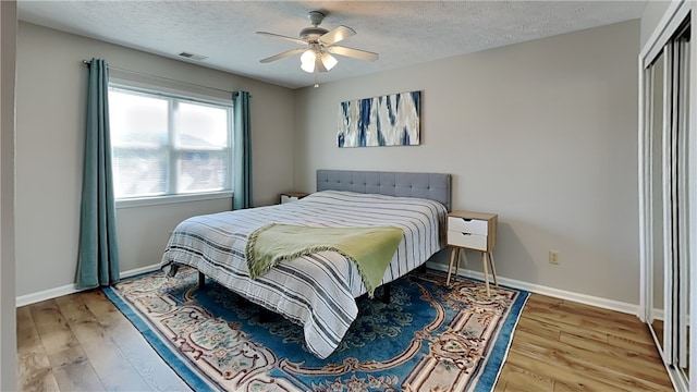 bedroom featuring a closet, wood-type flooring, ceiling fan, and a textured ceiling