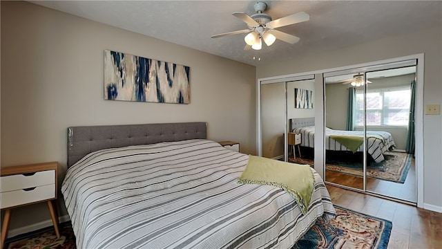 bedroom with wood-type flooring, two closets, and ceiling fan