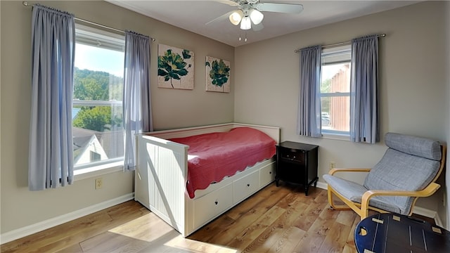 bedroom featuring light wood-type flooring, multiple windows, and ceiling fan