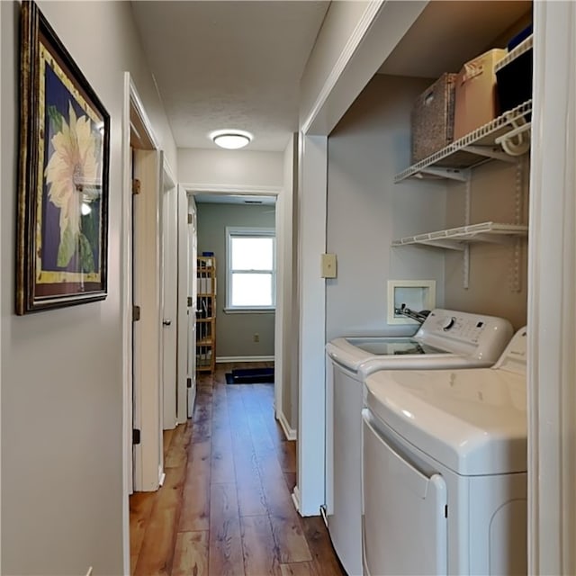 clothes washing area featuring wood-type flooring and washer and clothes dryer