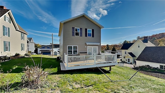 rear view of property with a garage, a lawn, and a deck