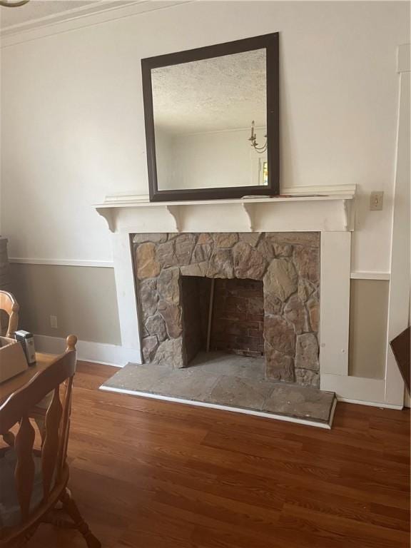 room details featuring a stone fireplace, crown molding, and hardwood / wood-style floors