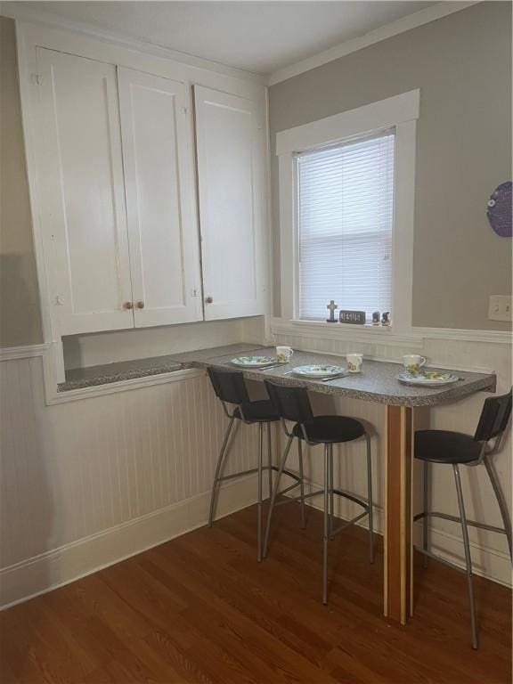 unfurnished dining area featuring dark wood-type flooring and ornamental molding