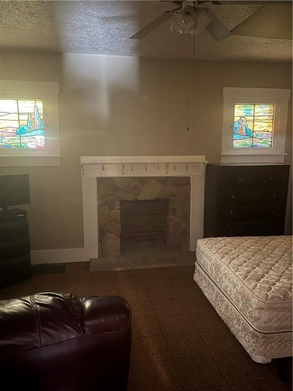 bedroom featuring a textured ceiling, ceiling fan, carpet floors, and a fireplace