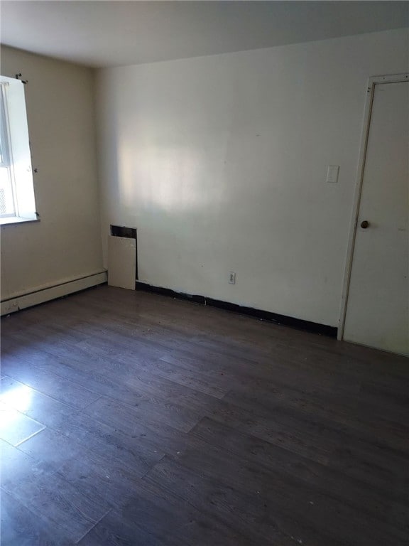 unfurnished room with a baseboard radiator and dark hardwood / wood-style floors