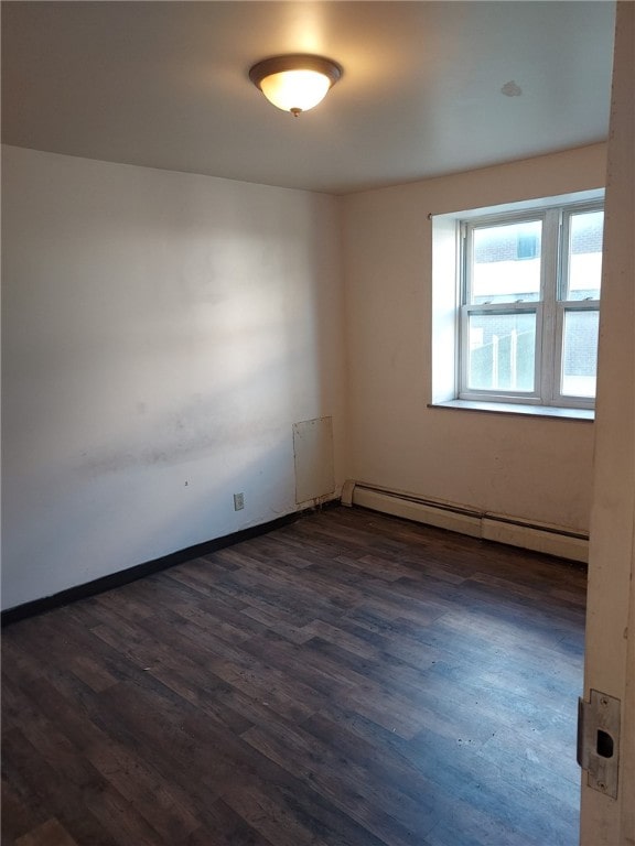 unfurnished room featuring dark wood-type flooring and a baseboard heating unit