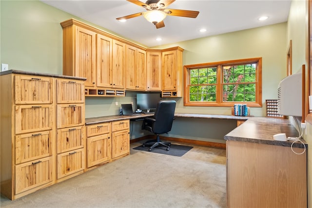 office space with ceiling fan, built in desk, and light colored carpet