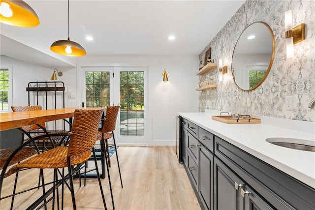 kitchen with gray cabinets, plenty of natural light, sink, and light hardwood / wood-style flooring