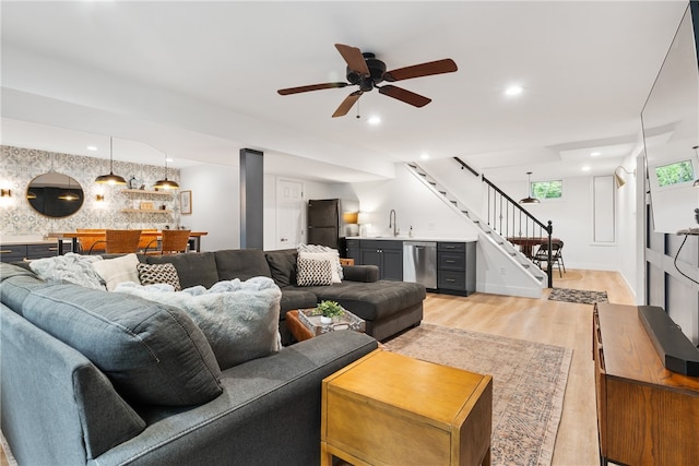 living room featuring wet bar, ceiling fan, and light hardwood / wood-style flooring