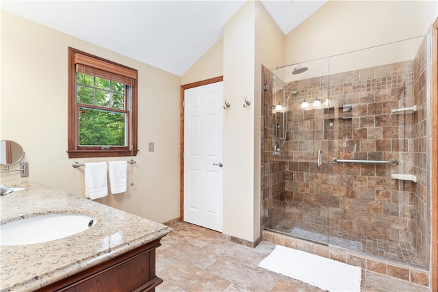 bathroom featuring a shower with door, vanity, and vaulted ceiling