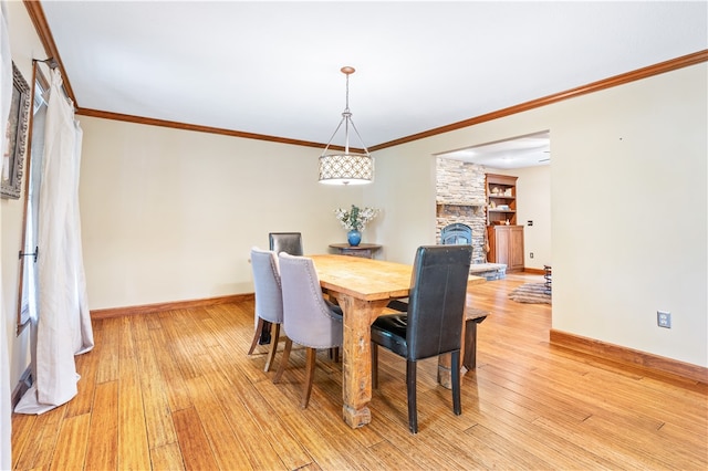 dining space with a fireplace, light hardwood / wood-style flooring, and crown molding