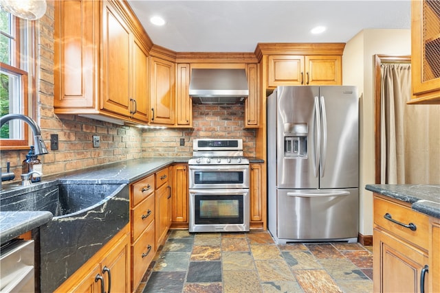 kitchen featuring decorative backsplash, appliances with stainless steel finishes, sink, and wall chimney exhaust hood