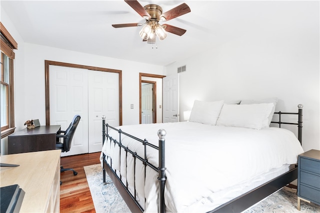 bedroom featuring multiple windows, light hardwood / wood-style flooring, ceiling fan, and a closet