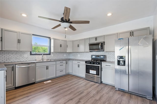 kitchen featuring ceiling fan, sink, tasteful backsplash, light hardwood / wood-style flooring, and stainless steel appliances