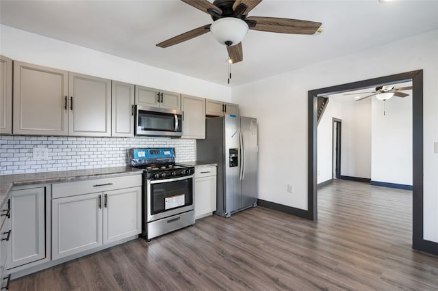 kitchen with gray cabinets, dark wood-type flooring, tasteful backsplash, appliances with stainless steel finishes, and ceiling fan