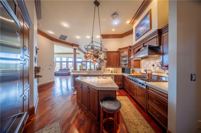 kitchen featuring appliances with stainless steel finishes, ornamental molding, a center island, and dark hardwood / wood-style floors