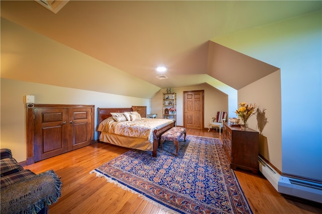 bedroom with light wood-type flooring, lofted ceiling, and a baseboard heating unit