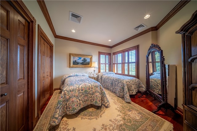 bedroom with ornamental molding, multiple closets, and dark wood-type flooring