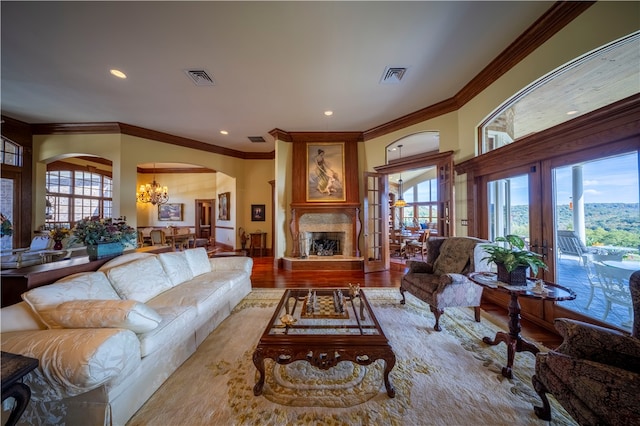 living room with an inviting chandelier, hardwood / wood-style flooring, plenty of natural light, and ornamental molding