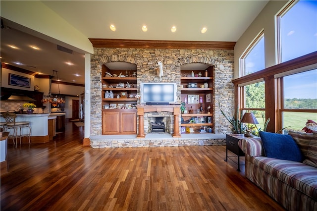 living room featuring a fireplace, ornamental molding, dark hardwood / wood-style flooring, and built in shelves