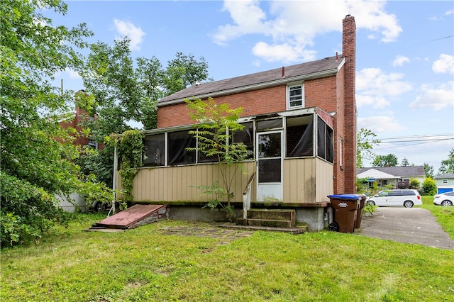 rear view of property with a yard and a sunroom