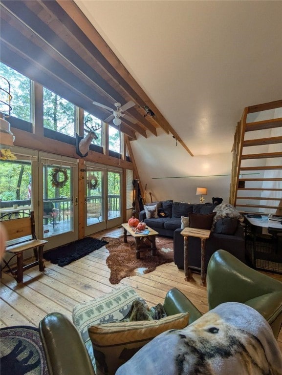 living room featuring a towering ceiling, ceiling fan, wood-type flooring, and beam ceiling