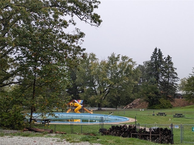 view of pool featuring a water slide, a lawn, and a playground