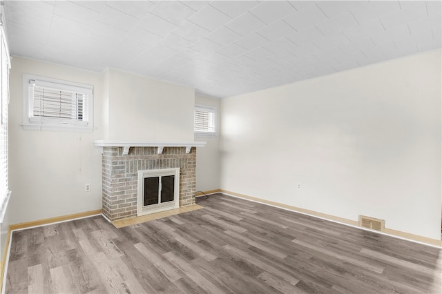 unfurnished living room featuring a brick fireplace and hardwood / wood-style floors