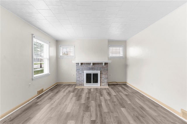 unfurnished living room with crown molding, light hardwood / wood-style flooring, and a brick fireplace