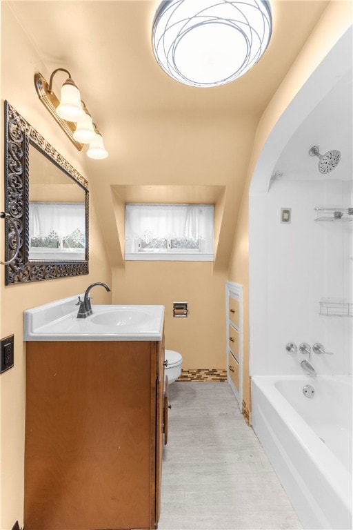 bathroom with a bathing tub, toilet, vanity, and a wealth of natural light