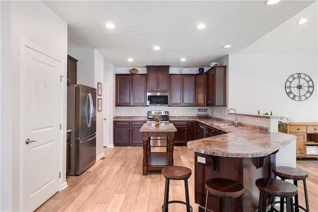 kitchen featuring kitchen peninsula, a kitchen breakfast bar, stainless steel appliances, and sink