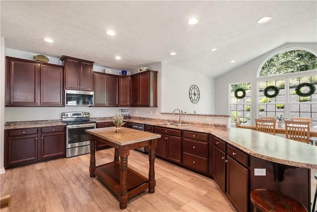 kitchen featuring sink, light hardwood / wood-style floors, vaulted ceiling, and appliances with stainless steel finishes