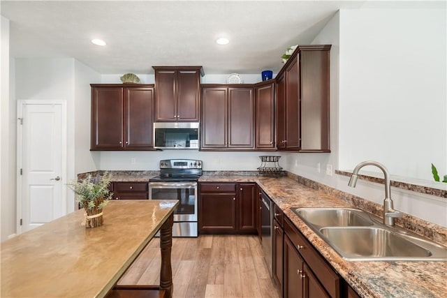 kitchen with sink, stainless steel appliances, dark brown cabinets, and light hardwood / wood-style flooring