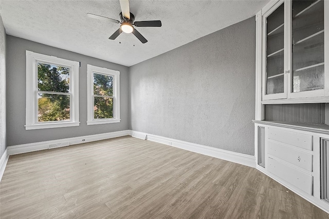 unfurnished room featuring ceiling fan, a textured ceiling, and light hardwood / wood-style flooring