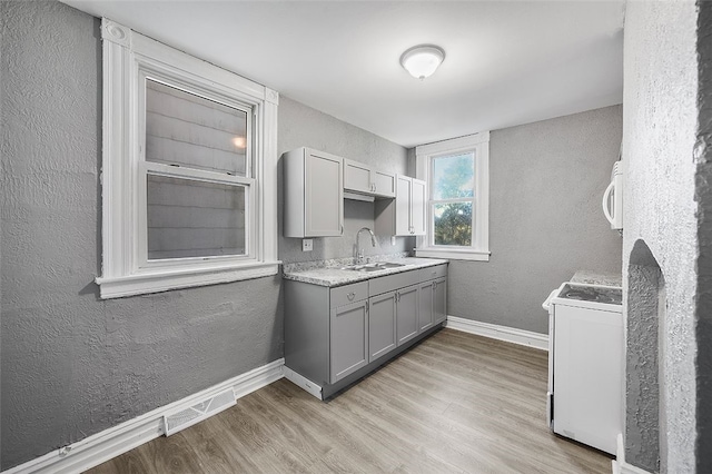 kitchen with light wood-type flooring, range, sink, and gray cabinets