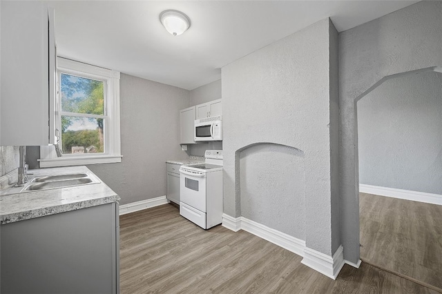 kitchen featuring light wood-type flooring, white appliances, sink, and white cabinets