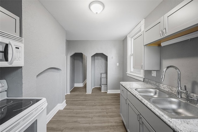 kitchen featuring light hardwood / wood-style floors, sink, white appliances, and gray cabinetry