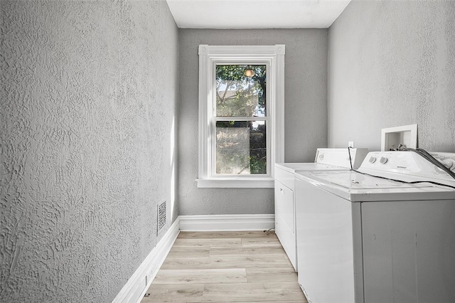 clothes washing area with light hardwood / wood-style floors and washer and dryer