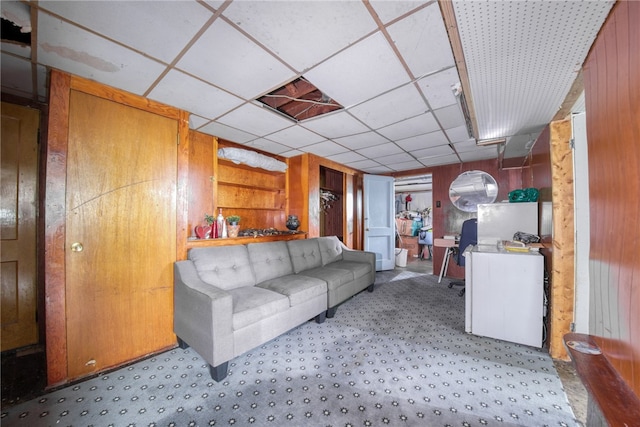 living room with a drop ceiling and wood walls